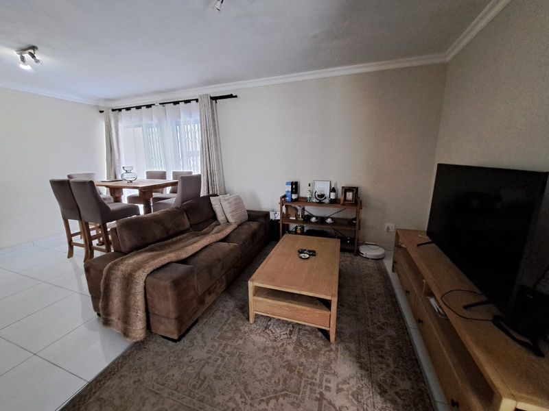An open-plan living and dining area featuring tiled flooring, neutral walls, and a sliding door providing access to the exterior.