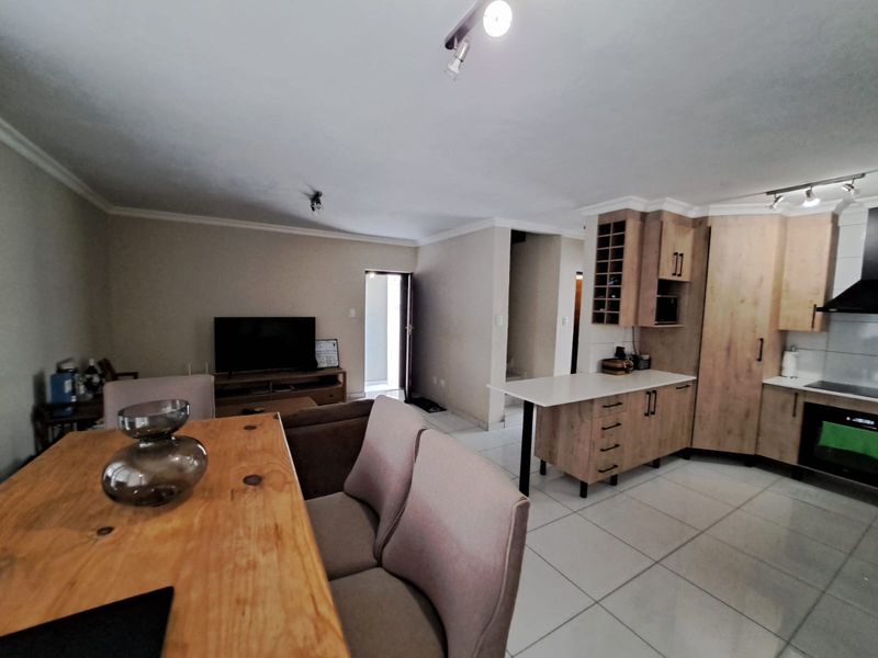 Open-plan living and kitchen area featuring light wood-finish cabinetry, a kitchen island, and tiled flooring throughout the space.