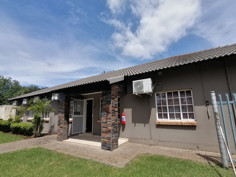 Front elevation of a single-story house featuring stone-clad pillars, a tiled roof, and a paved walkway leading to the entrance.