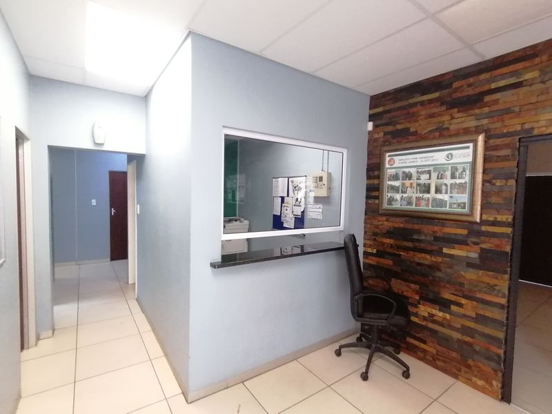 Office space featuring a reception window with a granite counter, a stone-clad feature wall, and neutral ceramic floor tiles.