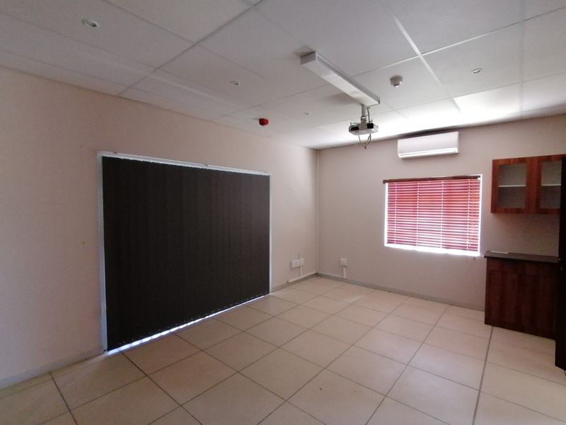 A functional office space featuring tiled flooring, a suspended ceiling, built-in cabinetry, and integrated climate control, suitable for a professional work environment.