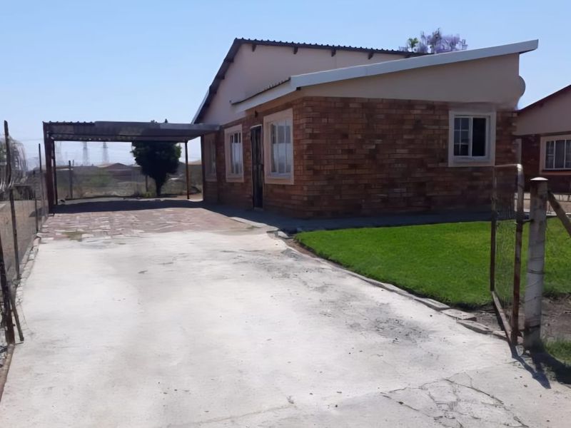 Front view of a single-story brick house featuring a concrete driveway, attached carport, and a small front lawn area.