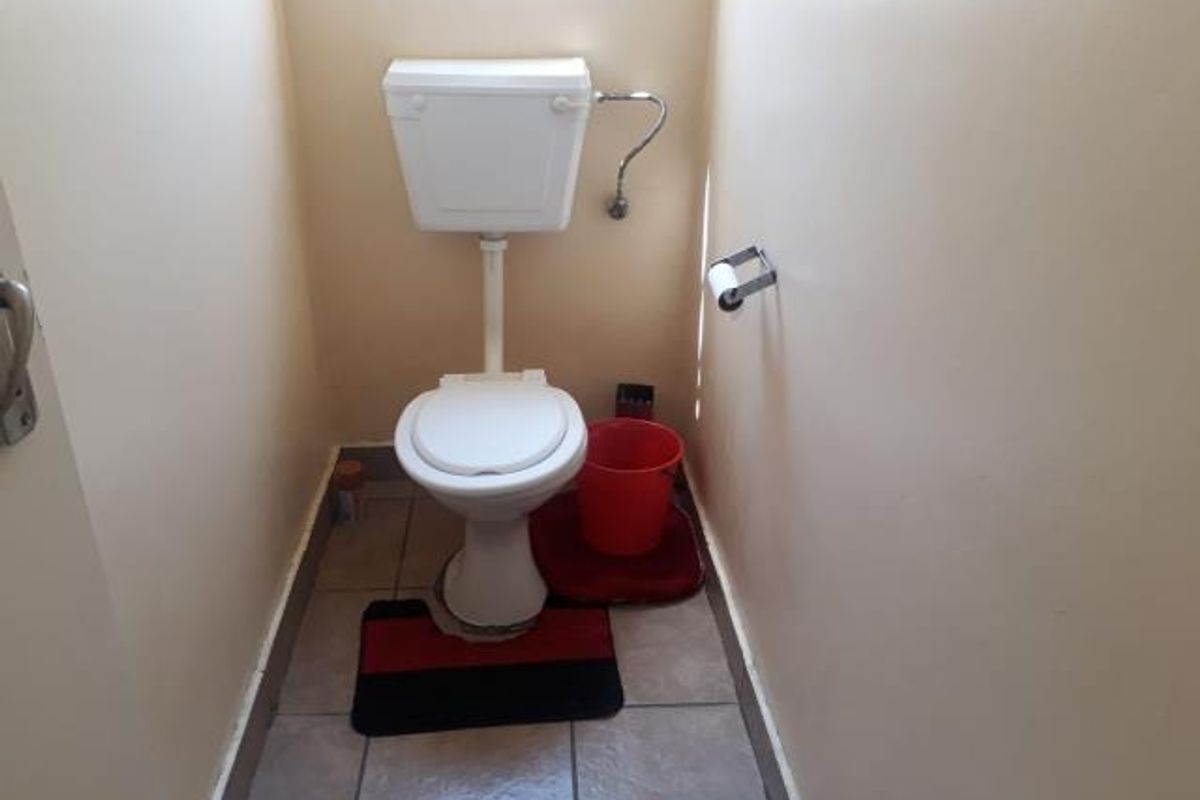 A compact, functional guest toilet featuring tiled flooring and standard sanitary fixtures.