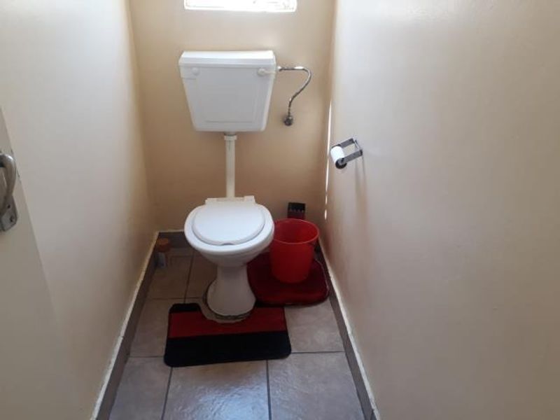 A compact, functional guest toilet featuring tiled flooring and standard sanitary fixtures.