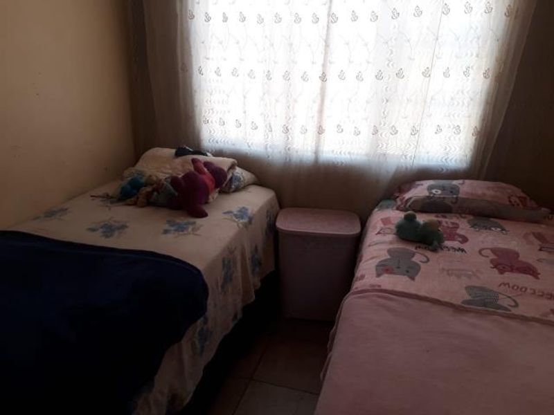 A functional bedroom featuring tiled flooring and a window with a curtain rail, providing a simple and practical living space.