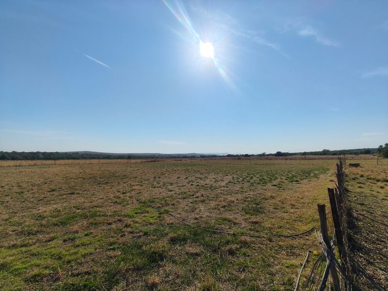 Expansive open farm land featuring natural landscape views and perimeter wire fencing with wooden posts.