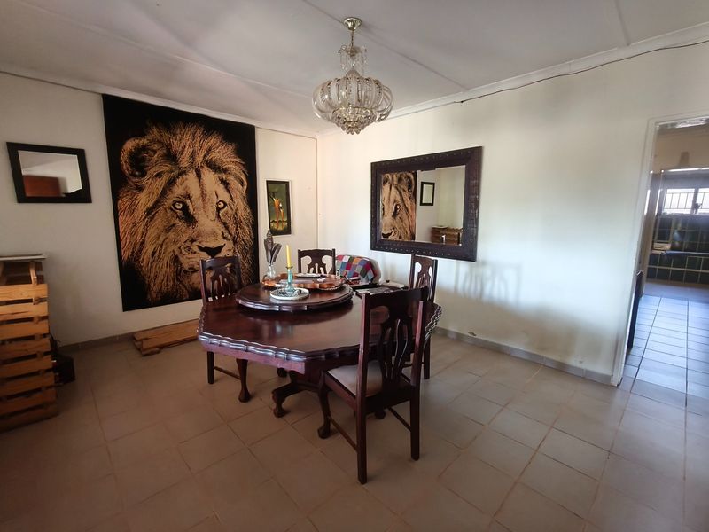 A dining room featuring tiled flooring and a central crystal chandelier, requiring cosmetic updates to the walls and ceiling.