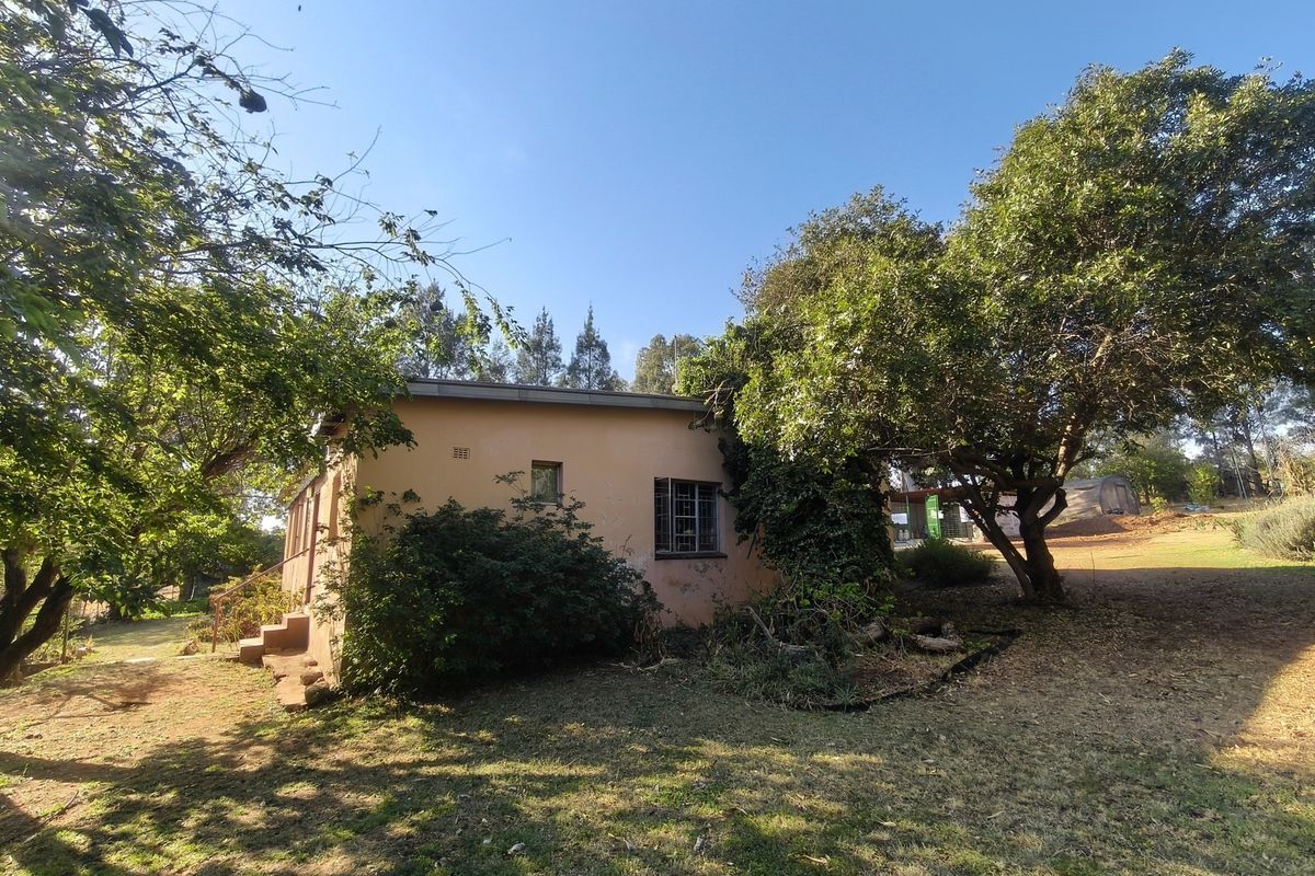 A view of the rear exterior of the farm dwelling, featuring a simple facade with steel-framed windows and concrete steps leading to an entrance.