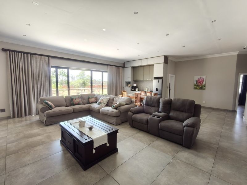 Spacious open-plan living area featuring large sliding doors, neutral tiled flooring, recessed lighting, and an integrated kitchen with modern cabinetry.