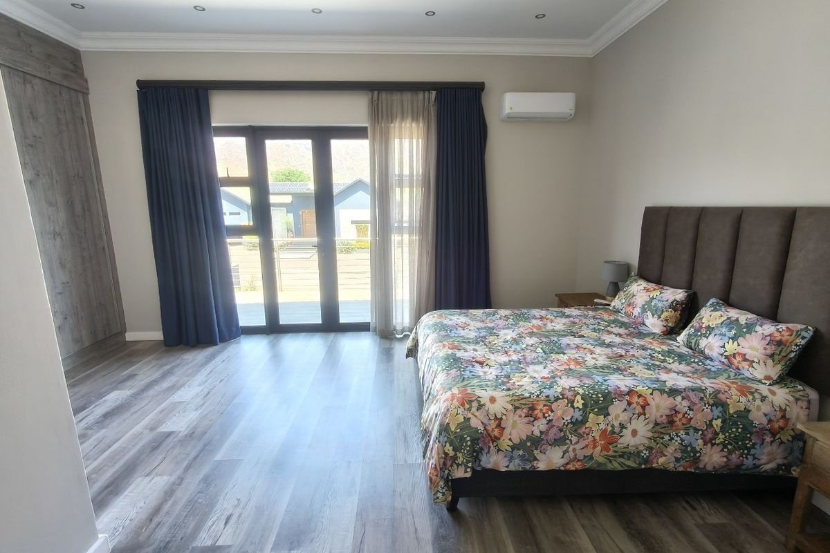 Spacious bedroom featuring modern laminate flooring, built-in cupboards, air conditioning, and a sliding glass door providing access to the exterior.