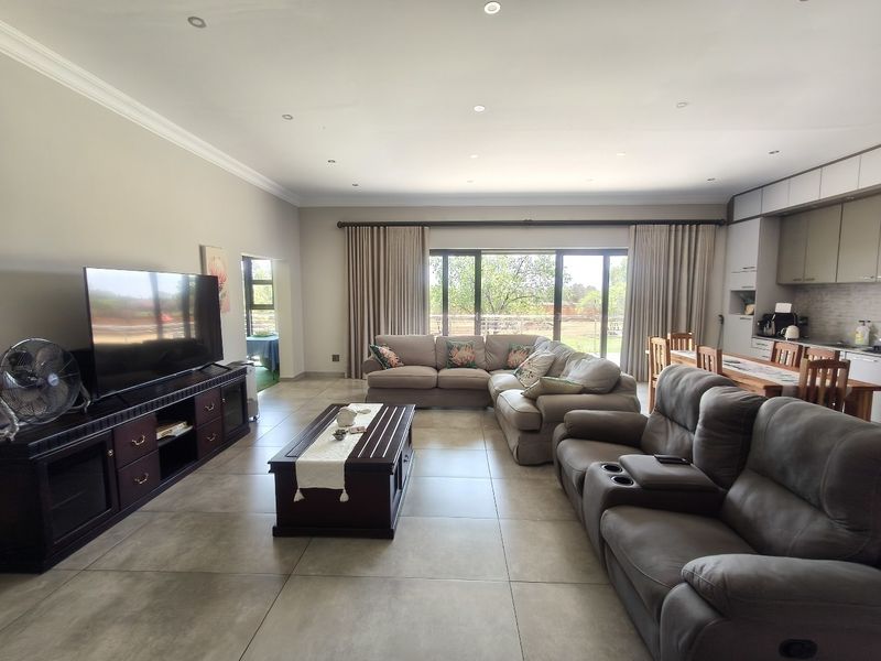 Spacious open-plan living area featuring large format floor tiles, recessed lighting, and seamless flow to the outdoor patio through sliding glass doors.