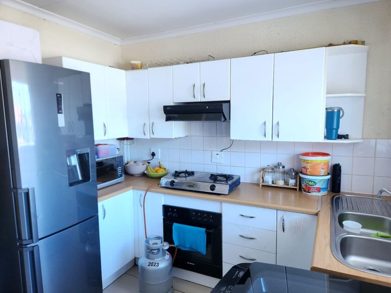 Functional kitchen featuring white cabinetry, laminate countertops, a gas hob with built-in oven, extractor fan, and a stainless steel sink.