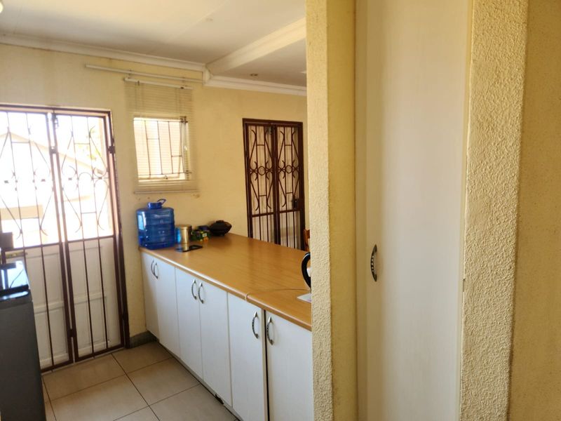 A functional scullery area featuring built-in cabinetry, laminate countertops, tiled flooring, and secure access doors.