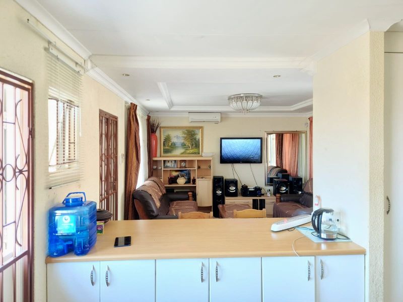 Open-plan living area featuring a kitchen breakfast bar, split-system air conditioning, and decorative ceiling finishes, connecting seamlessly to the adjacent lounge space.