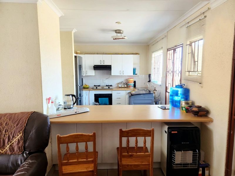 Functional kitchen featuring built-in cabinetry, gas hob, extractor fan, oven, and a breakfast bar counter, with direct access to the exterior.