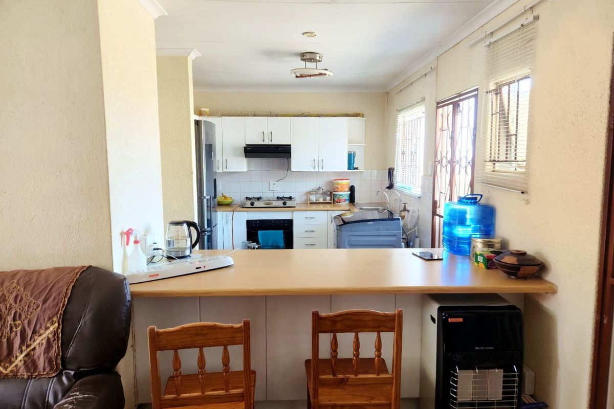 Functional kitchen featuring built-in cabinetry, gas hob, extractor fan, oven, and a breakfast bar counter, with direct access to the exterior.
