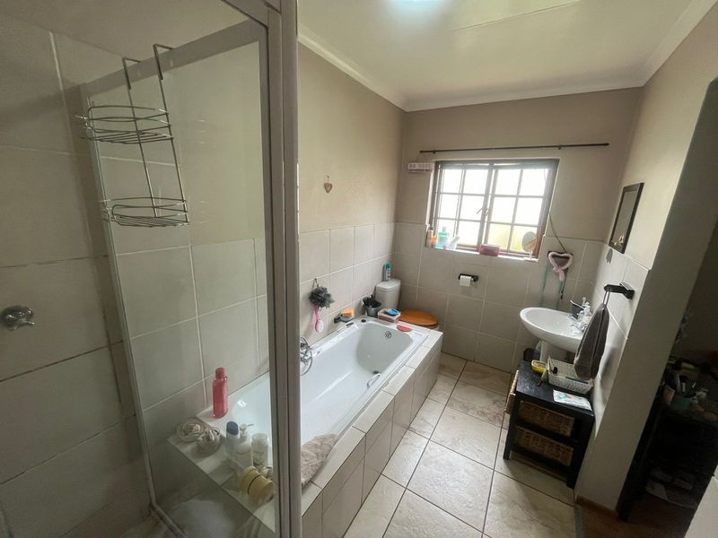 A functional bathroom featuring a built-in bathtub, separate shower enclosure, pedestal basin, and toilet with tiled finishes throughout.