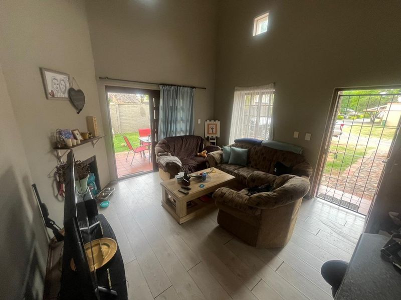 A living room featuring tiled flooring, a high ceiling, a fireplace, and direct access to the outdoor patio area through a sliding glass door.