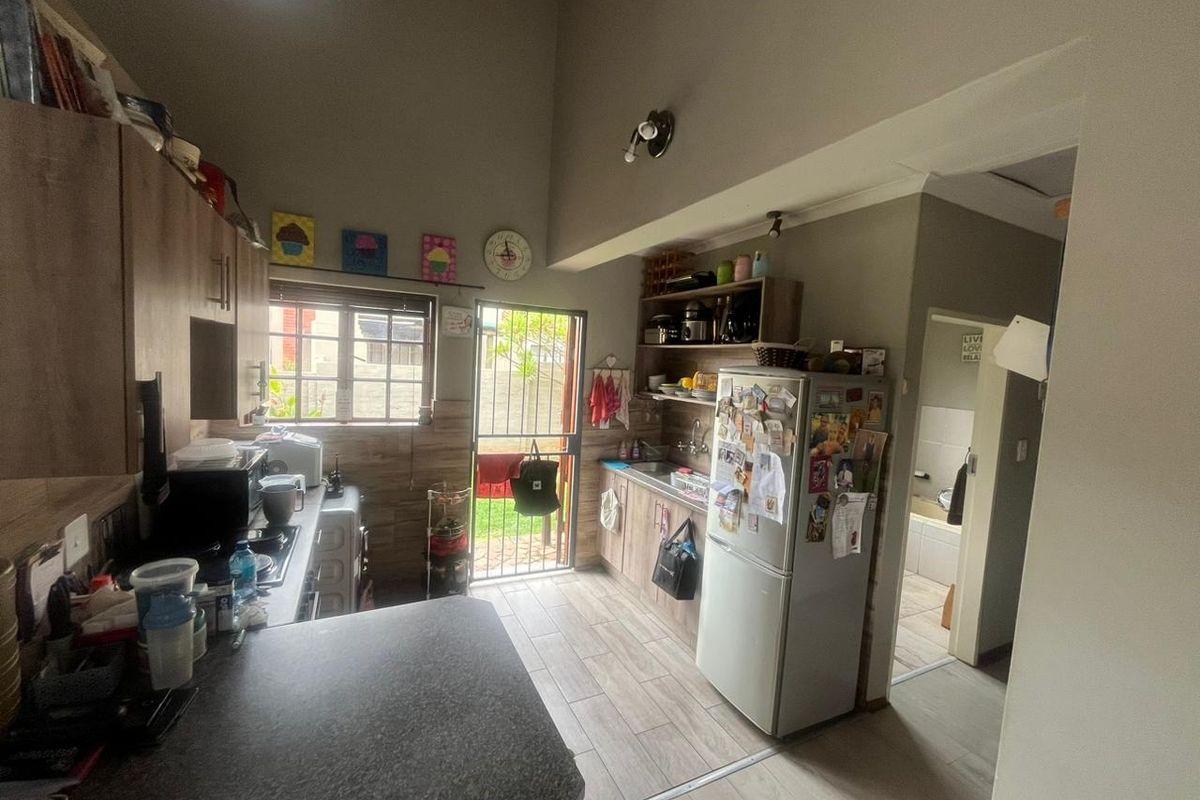 Functional kitchen featuring built-in cabinetry, laminate countertops, and direct access to the rear exterior area through a security gate.