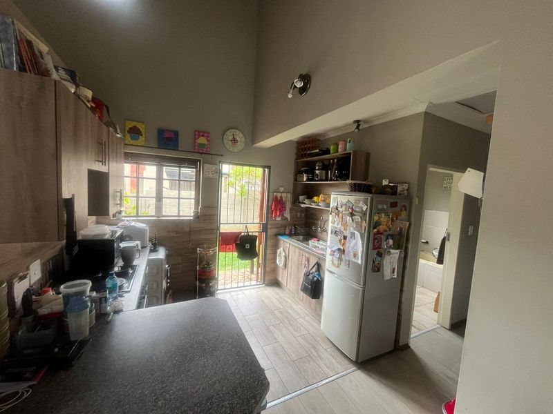 Functional kitchen featuring built-in cabinetry, laminate countertops, and direct access to the rear exterior area through a security gate.