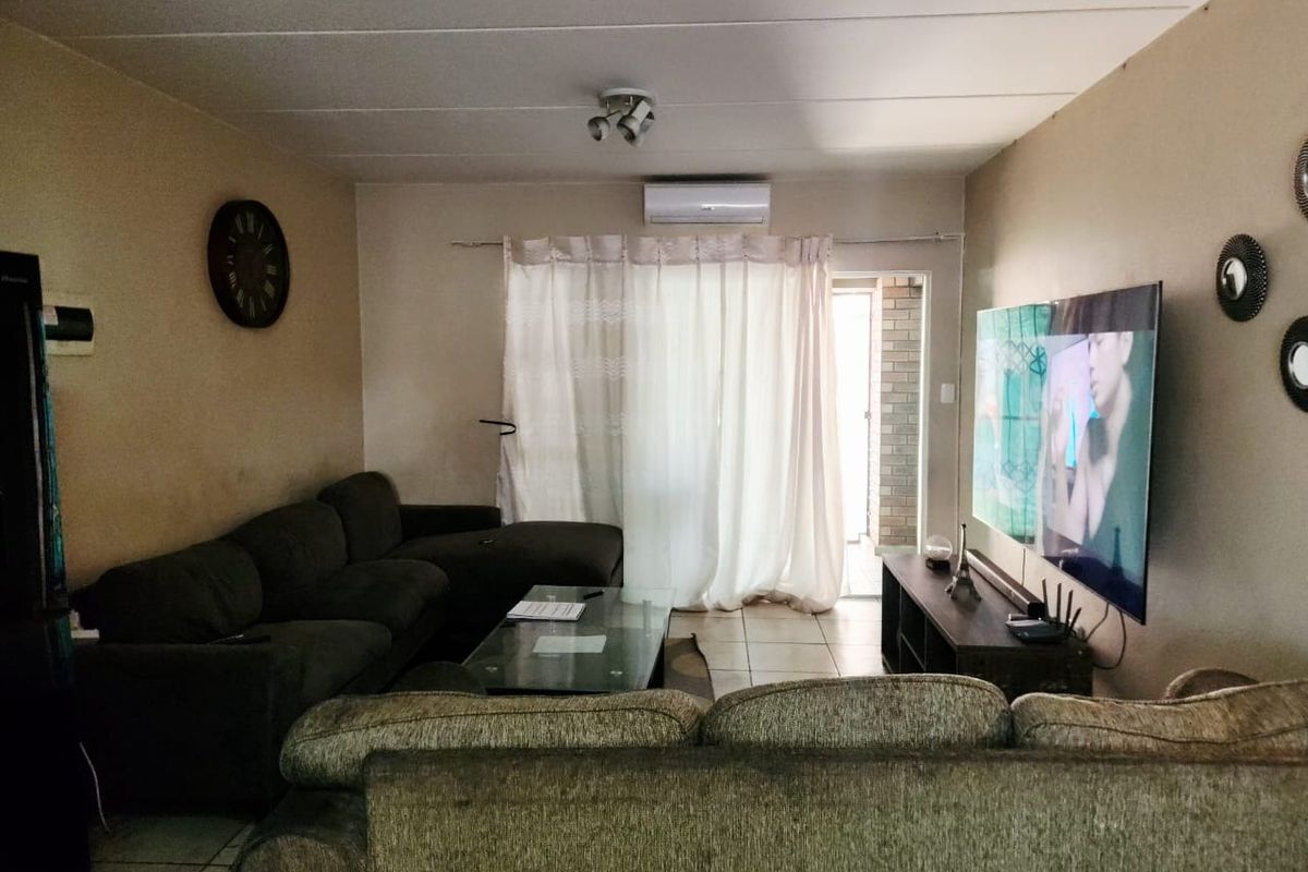 A living room featuring tiled flooring, an air conditioning unit, and a sliding glass door leading to an outdoor area.