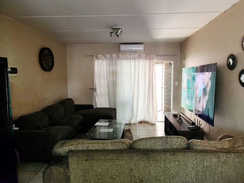 A living room featuring tiled flooring, an air conditioning unit, and a sliding glass door leading to an outdoor area.