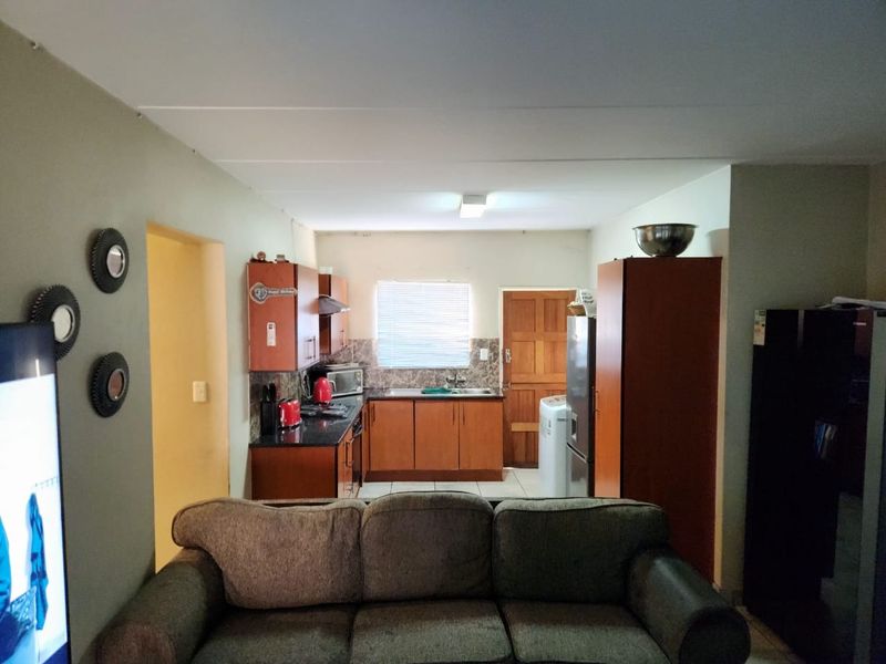 Open plan living area featuring a functional kitchen with built-in cabinetry, dark countertops, and integrated appliances, seamlessly connected to the main living space.