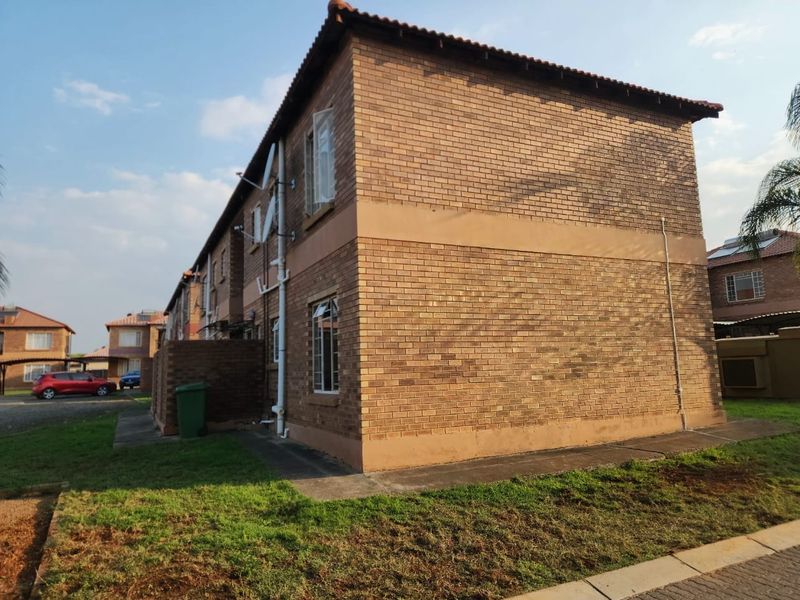 A side and rear view of a two-story face brick apartment building featuring tiled roofing and standard casement windows.