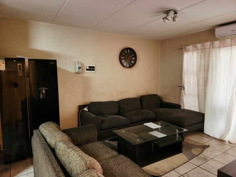 A living room featuring tiled flooring, a wall-mounted split-system air conditioner, and neutral wall finishes.