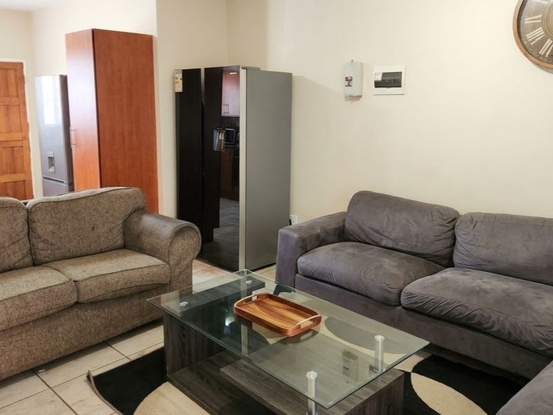 Open-plan living area featuring tiled flooring and a connected kitchen space with wooden cabinetry and countertops.