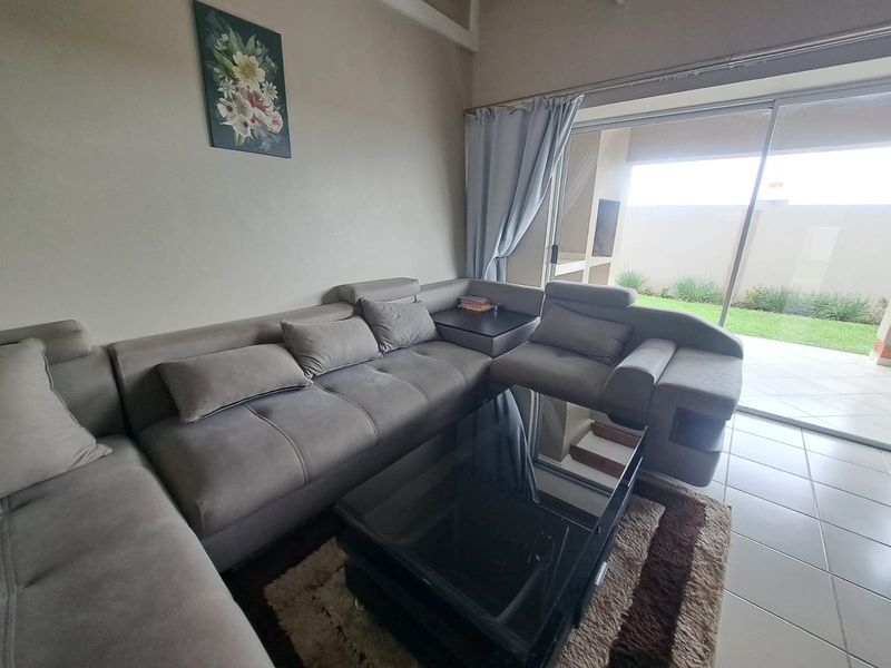 A living room featuring tiled flooring and a large sliding glass door providing access to the outdoor patio area.