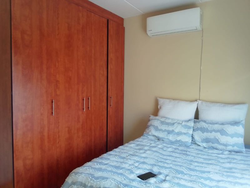 A bedroom featuring a large built-in wooden wardrobe and a wall-mounted split-system air conditioning unit.