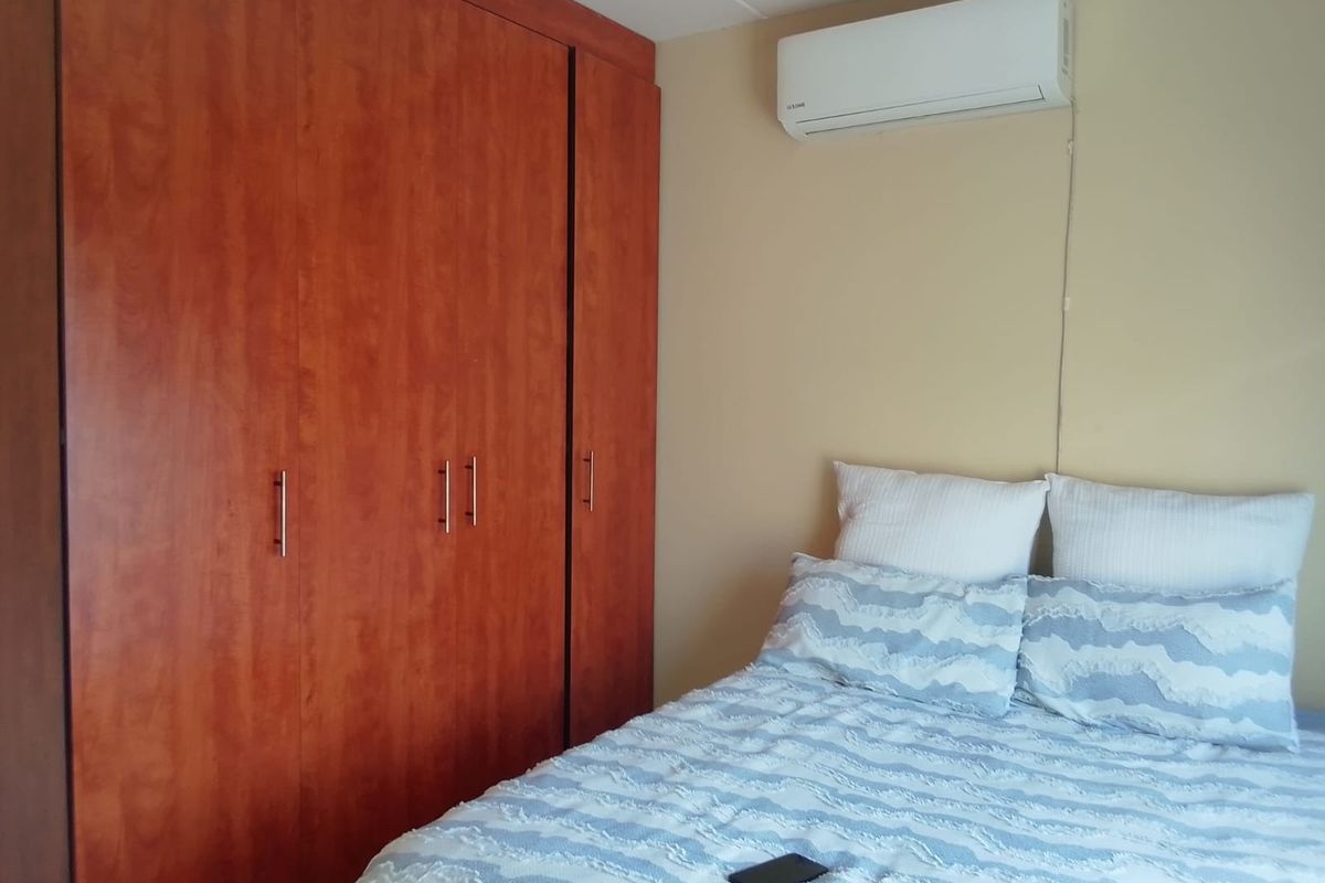 A bedroom featuring a large built-in wooden wardrobe and a wall-mounted split-system air conditioning unit.
