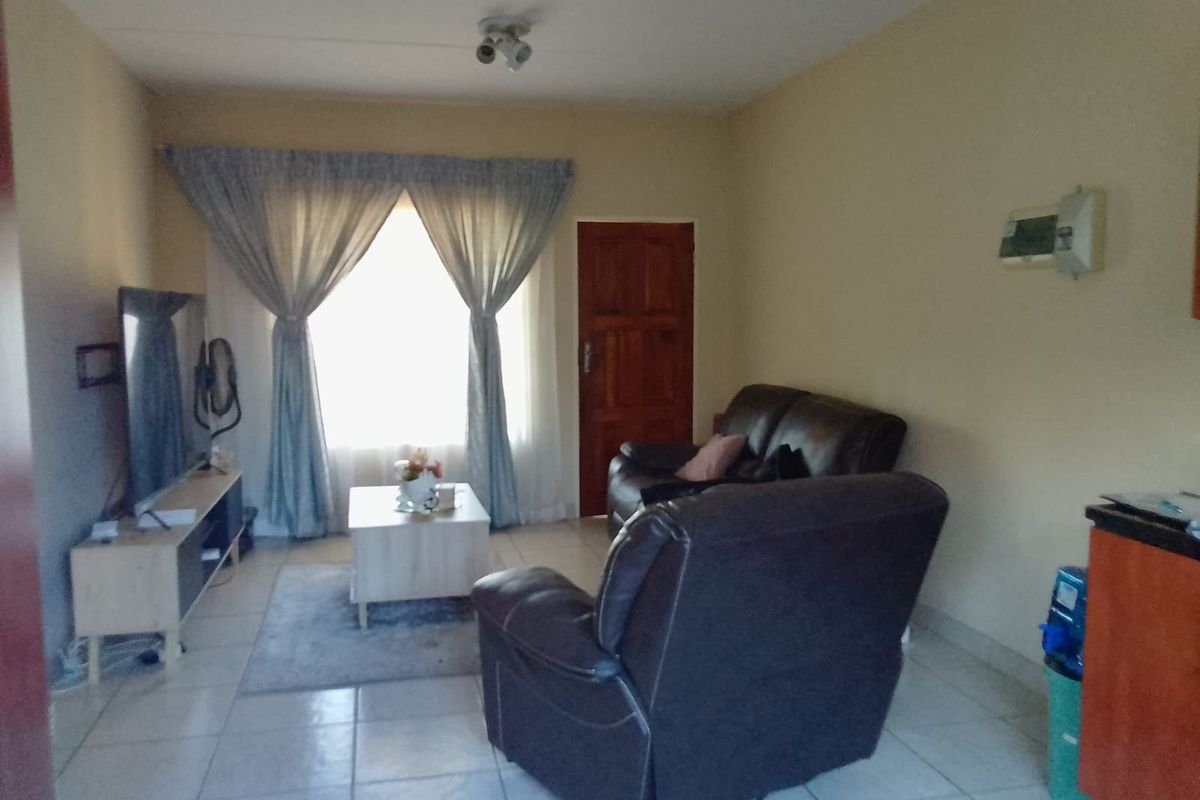 A functional living room area featuring tiled flooring and a timber entrance door, providing a neutral base for potential interior updates.