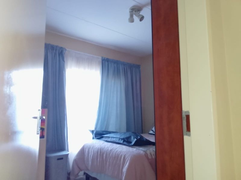 A view into a bedroom featuring a ceiling-mounted light fixture and window treatments, captured from the doorway.