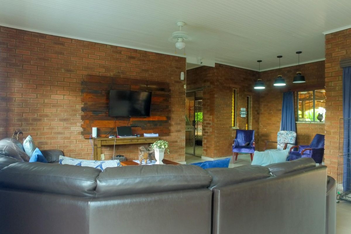 Spacious living area featuring rustic exposed brick walls, a tongue and groove ceiling, and integrated pendant lighting.