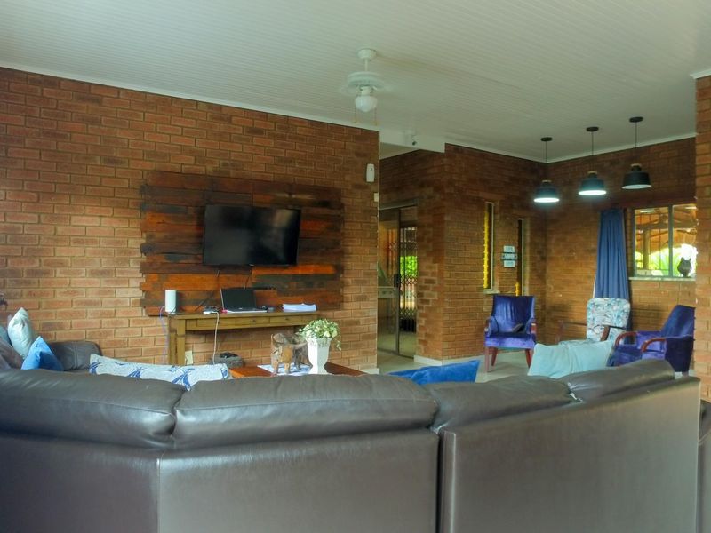 Spacious living area featuring rustic exposed brick walls, a tongue and groove ceiling, and integrated pendant lighting.