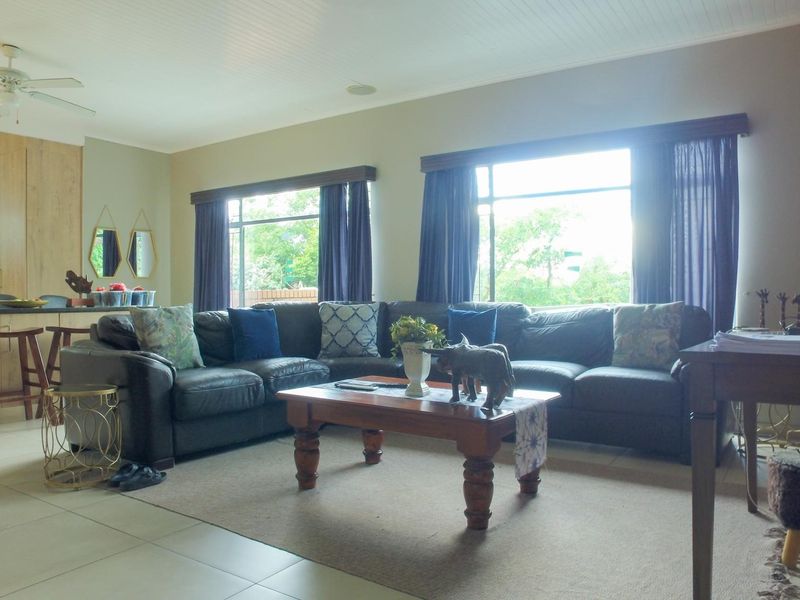 Spacious open-plan living area featuring tiled floors, an exposed brick feature wall, and a modern kitchen with a central island.
