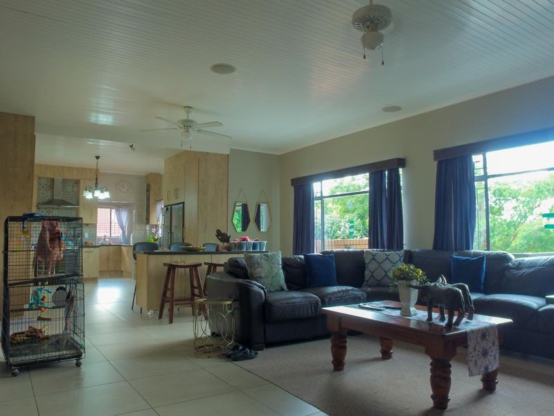 Spacious open-plan living area featuring a modern kitchen with island, tiled floors, exposed brick accents, and a bright, airy atmosphere with large windows.