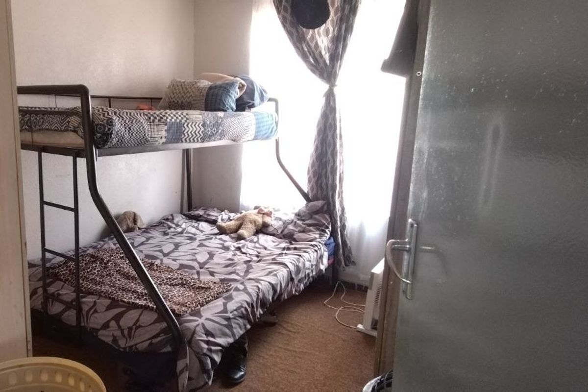 A compact bedroom featuring carpeted flooring and natural light from a window, suitable for a single or bunk bed configuration.