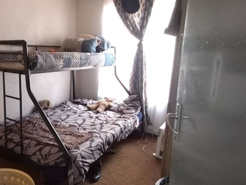 A compact bedroom featuring carpeted flooring and natural light from a window, suitable for a single or bunk bed configuration.