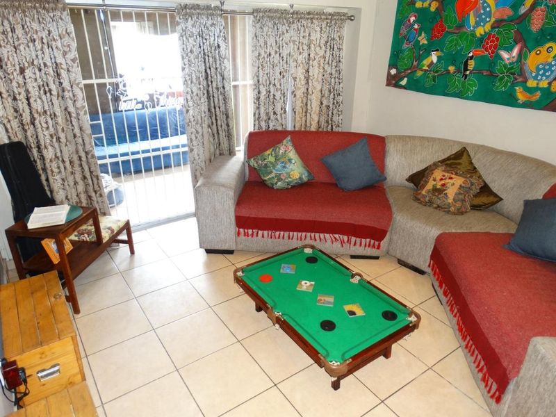A living room area featuring tiled flooring and a sliding door with an integrated security gate leading to an outdoor space.
