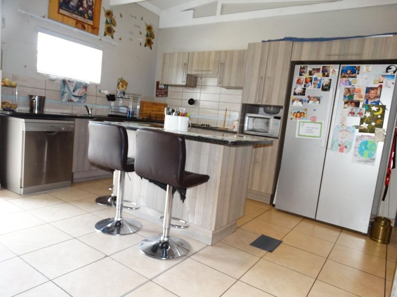 A functional kitchen featuring laminate cabinetry, granite countertops, a breakfast bar, and tiled flooring, providing a practical layout for daily meal preparation.