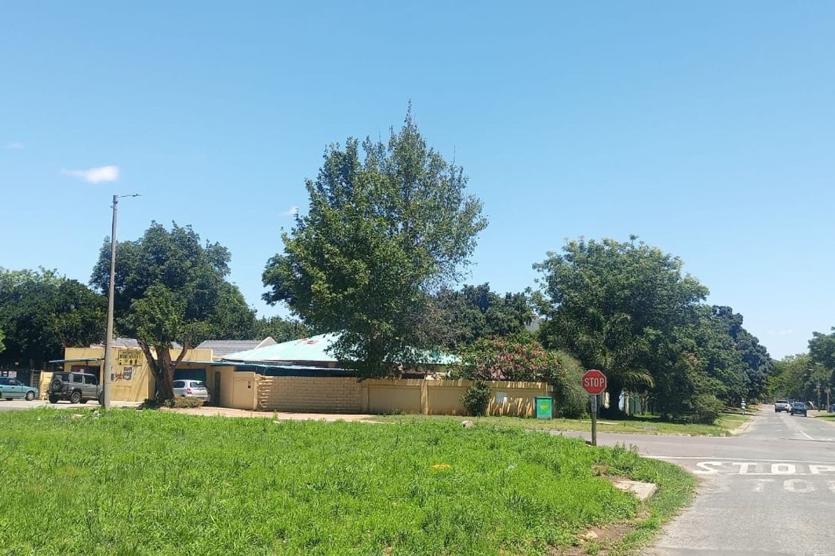 A street-level view showing the property boundary wall, surrounding vegetation, and local road infrastructure in a residential neighborhood.