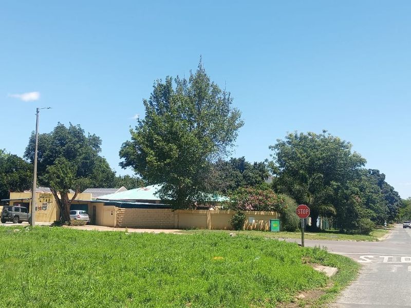 A street-level view showing the property boundary wall, surrounding vegetation, and local road infrastructure in a residential neighborhood.