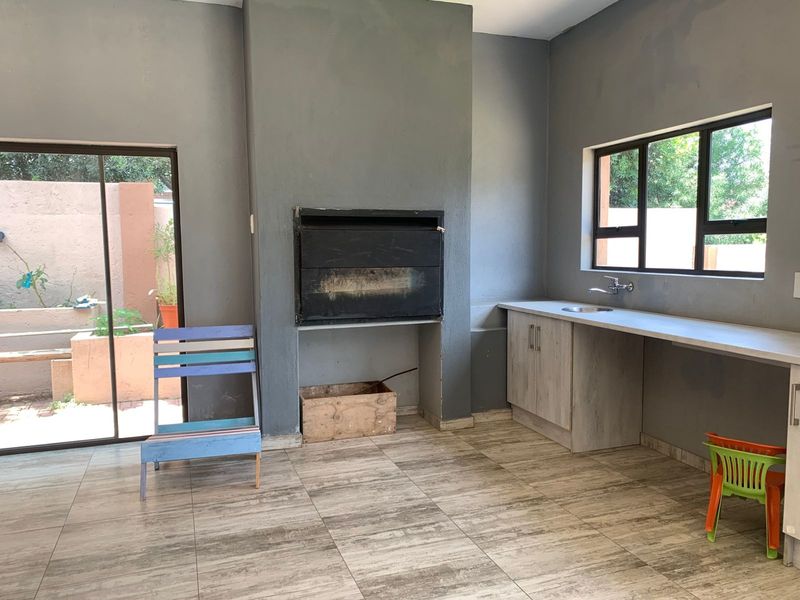 Covered patio area featuring a built-in braai, sink with base cabinetry, and direct access to the garden through a sliding door.