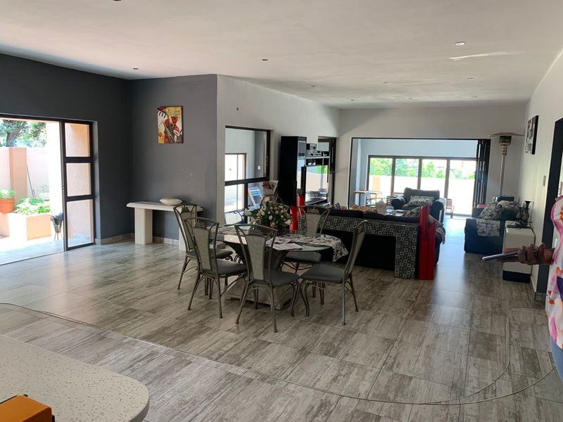Spacious open-plan living and dining area featuring modern tiled flooring, recessed lighting, and large sliding glass doors providing access to the outdoor space.