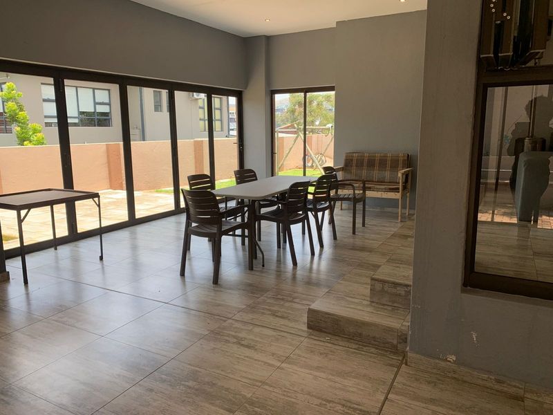 Spacious open-plan living area featuring large aluminium sliding doors, tiled flooring, and recessed lighting, offering seamless access to the outdoor space.