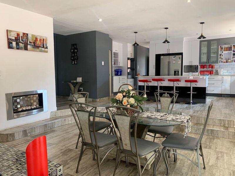 Spacious open-plan living and dining area featuring a modern kitchen with island, built-in fireplace, and contemporary tiled flooring throughout.