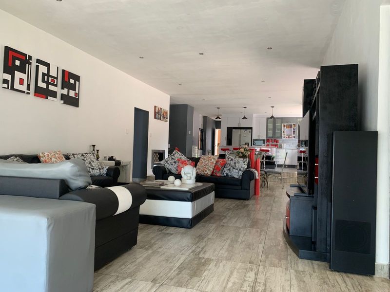 Spacious open-plan living area featuring tiled flooring, recessed lighting, and a seamless flow into a modern kitchen with a central island.
